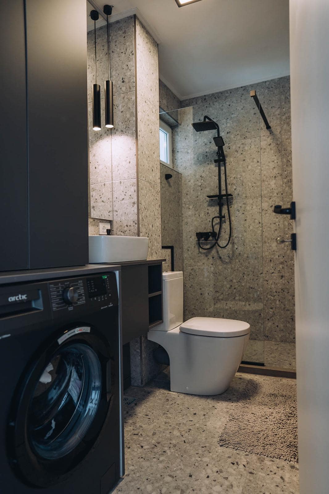 Baie compactă placată cu terrazzo, cu duș la nivel și mașină de spălat integrată